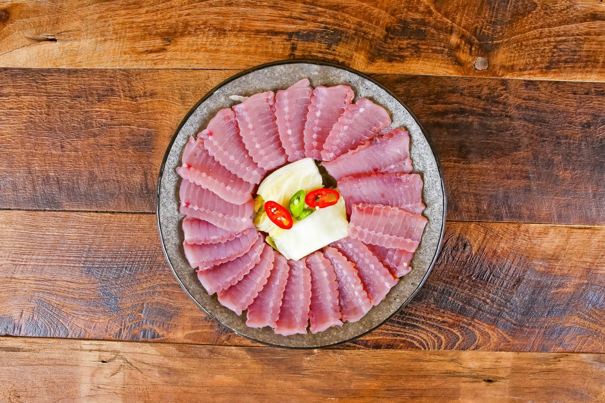 나무 테이블 위 홍어회 — 원형 접시에 방사형으로 배열한 생홍어